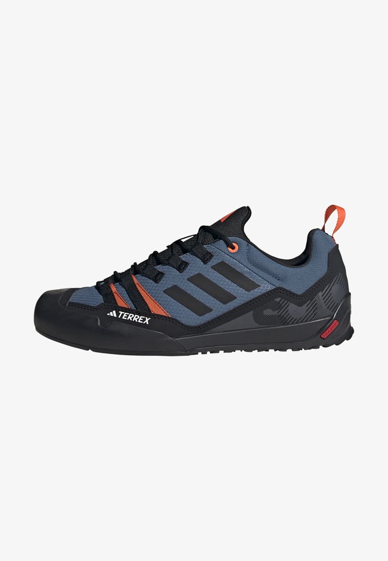 Black and gray climbing shoes featuring a mesh upper with orange accents, a reinforced toe cap, and a textured rubber sole for grip.