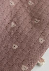Tekstil i blød mauve med lodrette striber. Har gentagne små bjørneansigtet i lys beige med mørke detaljer. Glat striktekstur.