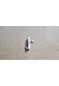 Susanne Kaufmann anti-aging light cream bottle on a gray surface with two small white flowers beside it.