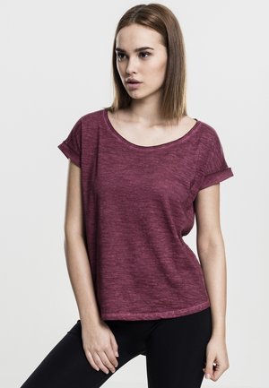 Burgundy short-sleeve t-shirt with a scoop neckline and rolled cuffs, made from textured, lightweight fabric. Model poses with black leggings.