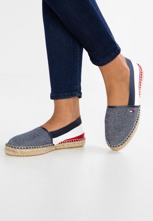 Espadrille shoe with a denim fabric upper in blue, white, and red accents; jute sole with a braided design; casual slip-on style.
