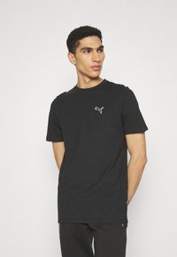 Sort kortærmet t-shirt lavet af bomuld, med et lille hvidt Puma-logo på brystet og en klassisk rund halsudskæring.
