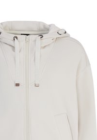 Licht beige hoodie met een volledige rits, voorzien van trekkoorden, metalen accenten en een voorkPocket. Zachte, gestructureerde stof.