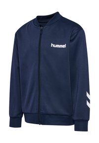 Veste zippée bleu marine avec col, poignets et bord-côtes, avec logo blanc « hummel » sur la poitrine et deux chevrons blancs sur la manche.