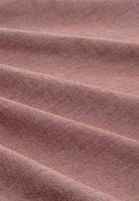 Tessuto di cotone in un colore rosa tenue, caratterizzato da una fine e sottile texture con rigature diagonali e morbido drappeggio, che mostra linee di superficie lisce.