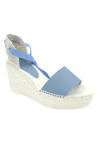 Espadrille azul con cuña y ancha tira de pie mate, tacón tejido en beige y lazos azules en el tobillo. Presenta una base envuelta en yute y un acabado texturizado.