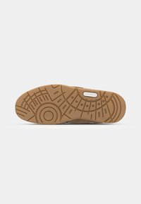 Lacoste sneaker sole in brown rubber, featuring a textured pattern with circular and linear details. Includes branded label in white.