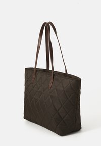 Donkerbruin gewatteerde totebag met twee lange leren handvatten, rechthoekige vorm, rechtopstaand op een witte achtergrond.
