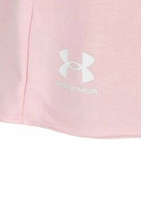 Camiseta deportiva de color rosa claro con una textura suave, con un logo blanco de Under Armour cerca del dobladillo. Diseño simple, mangas cortas.