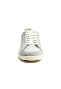 Lichtgrijze sneaker met een gladde leren en suede bovenzijde, witte veters, rode accenten en een gestructureerde rubberen zool.