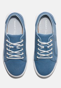 Sneakers in tela blu con lacci bianchi e suole in gomma. Presentano un colletto imbottito e un dettaglio di branding sul lato. Texture liscia generale.