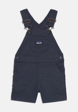 Marineblaue Denim-Latzhose mit verstellbaren Trägern, kupferfarbenen Beschlägen, einer Vordertasche und zwei Seitentaschen; versehen mit sichtbaren Stickdetails.