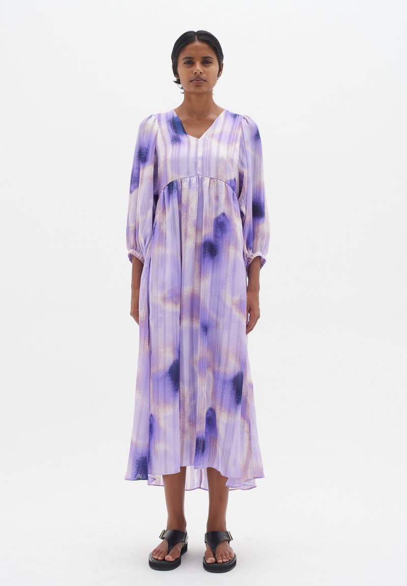 Purple tie-dye dress with a V-neck and long puff sleeves. Made of lightweight fabric, featuring subtle pleats and a slightly flared hem.