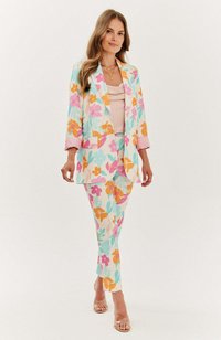 Květinový oblek v pastelových modrých, růžových a oranžových barvách. Sako má klopový límec a odpovídající kalhoty s přiléhavým střihem.