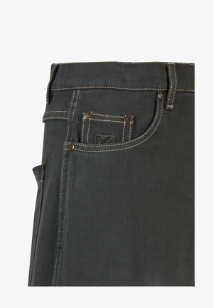 Pantalons en denim gris foncé avec des coutures beige contrastantes, comportant une poche arrière avec une étiquette de logo et des détails de rivets métalliques.