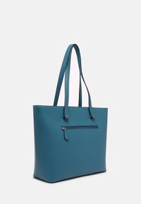 Sac fourre-tout en similicuir bleu sarcelle avec deux bretelles, une poche zippée à l'avant et une forme structurée. Texture lisse et design minimaliste.