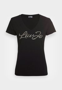 Camiseta negra de cuello en V hecha de algodón, con un logo de script con lentejuelas en la parte frontal. Manga corta con un corte ajustado.