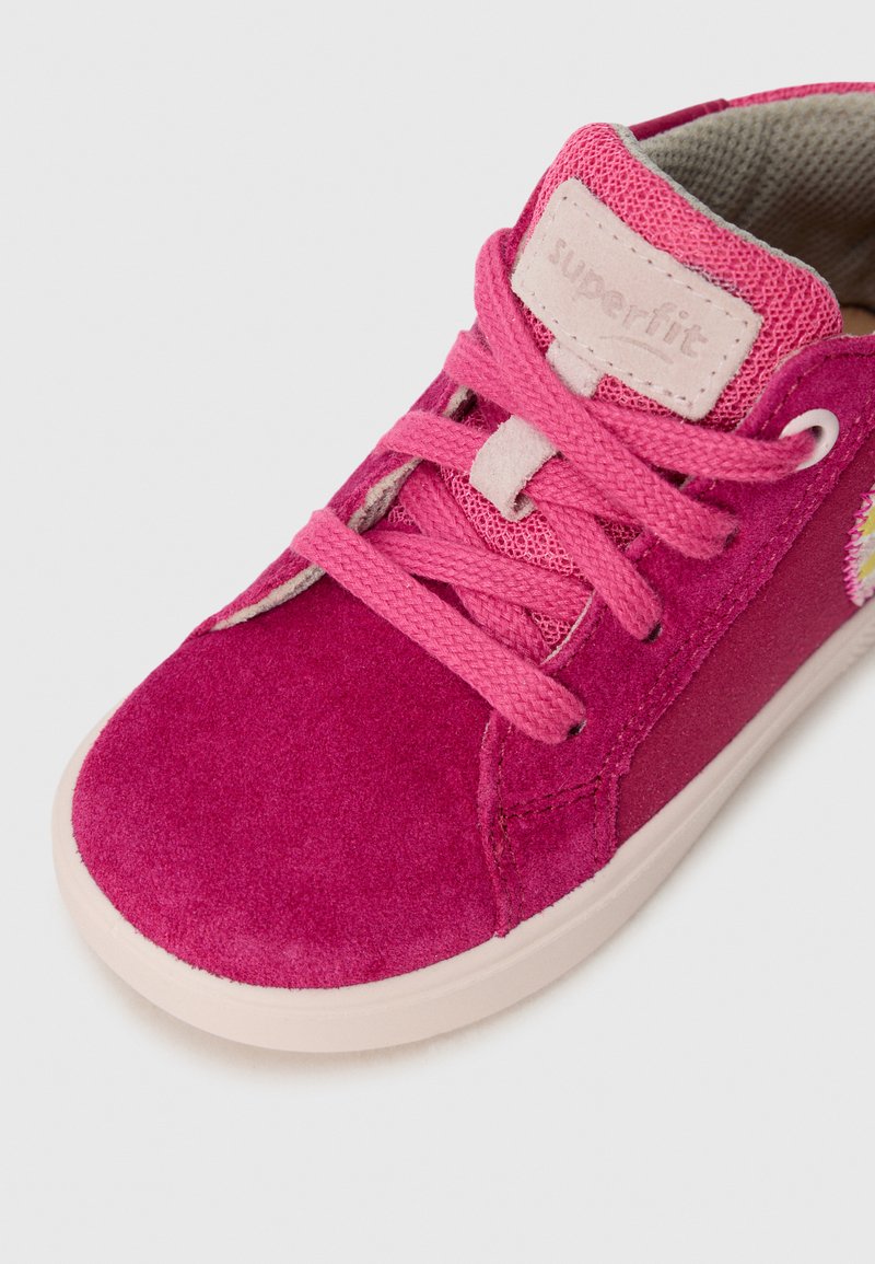 Rosa Wildledersneaker mit passenden Schnürsenkeln, verstärkten Nähten und einer strukturierten Zunge. Hat ein farbenfrohes Blumenakzent an der Seite.