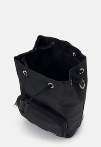 Sort bucket taske lavet af nylon med snorelukning, sølvfarvet hardware og en frontlomme med lynlås til ekstra opbevaring.