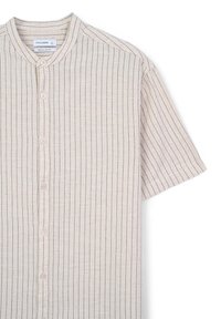 Camicia a maniche corte color beige chiaro con colletto alto, caratterizzata da sottili righe verticali e cinque bottoni sul davanti.