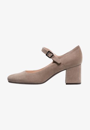 Chaussure Mary Jane en suède beige avec un bout arrondi, une bride au niveau de la cheville et un talon moyen bloc. Texture lisse avec un design simple et sans motifs.
