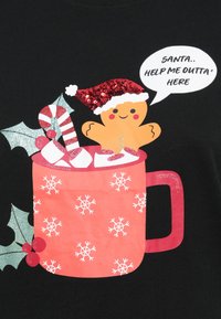 Ingefærmand iført en rød glitrende nissehue i en rød kop med snefnug, sammen med en pebermyntepind og skumfiduser, som siger: "Julemand.. hjælp mig ud herfra."