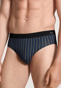 Zwart en blauw gestreepte slips met een effen zwarte tailleband. De stof heeft een gladde textuur met verticale lijnen in verschillende breedtes.