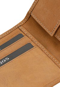 Portafoglio in pelle marrone chiaro con molteplici scomparti per carte, cuciture visibili e una superficie liscia. Due carte parzialmente inserite mostrano facce nere.