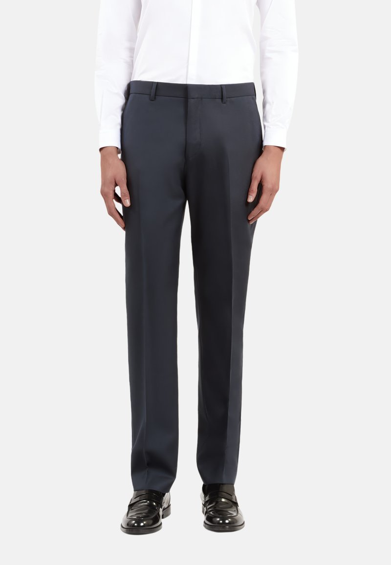 Donkerblauwe op maat gemaakte broeken van gladde stof, ontworpen met een rechte pijp en een subtiele voorplooi, gecombineerd met zwarte glanzende loafers.