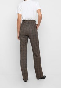 Pantalons à carreaux marron taille haute avec une coupe droite, présentant une texture lisse, des poches latérales et une taille ajustée.