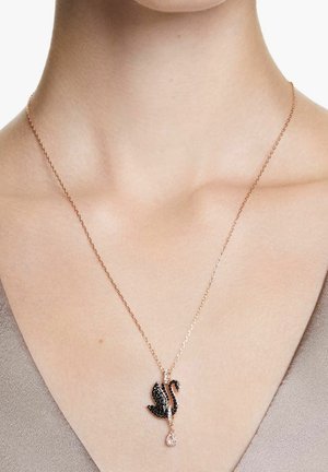 Collier pendentif en forme de cygne orné de cristaux noirs et transparents sur une chaîne en or rose avec un accent en forme de goutte. La chaîne est délicate et maillée.