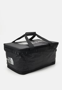 Black insulated cooler bag with a rectangular shape, thick carry handles, zipper closure, and a large logo printed on the top.