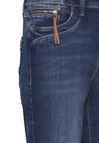 Jeans de denim oscuro con corte ajustado, costuras en contraste y un bolsillo frontal con cremallera y tirador de cuero marrón. Textura suave.