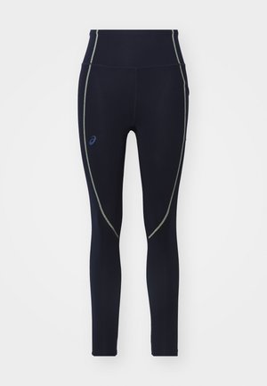 Marineblauwe high-waisted leggings van rekbaar materiaal, met groene stiksels en een Asics-logo aan de linkerkant.
