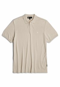Béžové polo triko vyrobené z měkké, texturované látky. Má límec, knoflíkovou légou se třemi knoflíky, krátké rukávy a malou nášivku na prsou.