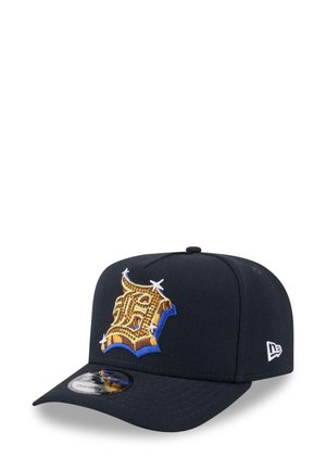 Navy baseball cap made of fabric featuring a prominent gold and blue embroidered logo. Flat brim with a circular logo patch on the visor.