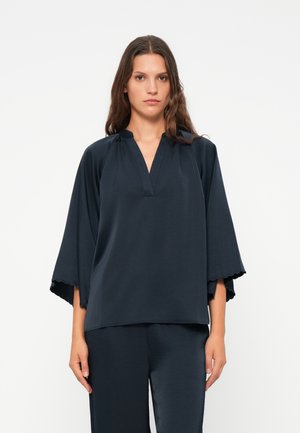Top blu scuro con una vestibilità comoda, scollo a V e maniche a tre quarti a campana con bordi scallop. Realizzato in tessuto morbido, abbinato a pantaloni coordinati.
