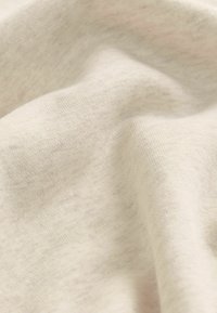 Lys beige stof med en blød, glat overflade, der har subtile nuancer i farven og et let stræk. 