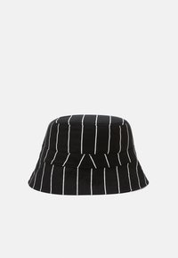 Svart bøttehatt med vertikale hvite striper, laget av stoff, med en rund topp og bred, nedadgående brem.
