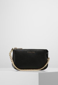 Clutch de cuero negro con un acabado texturizado, cadena dorada, cierre de cremallera y logotipo en relieve en la parte delantera. Diseño compacto y rectangular.