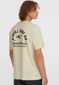 Lichtbeige korte mouwen t-shirt gemaakt van katoen. Bevat zwarte bedrukte tekst en logo op de achterkant. Rechte zoom, comfortabele pasvorm en ronde halslijn.