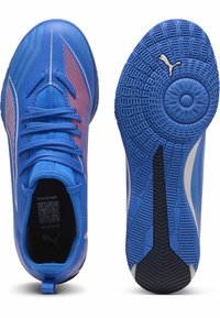 Scarpe da ginnastica blu con tomaia testurizzata, dettagli rossi e bianchi, chiusura con lacci e suola in gomma con motivo e grip circolare.