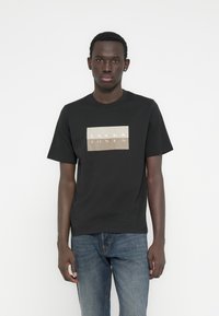 Μαύρο βαμβακερό t-shirt με κοντά μανίκια, με ορθογώνιο λογότυπο "JACK & JONES" σε χρώμα κρεμ και χρυσό τυπωμένο στο μπροστινό μέρος.