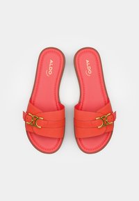 Sandales orange à glisser avec deux brides et un détail de boucle dorée. Matériau doux, forme arrondie et semelle plate en brun.