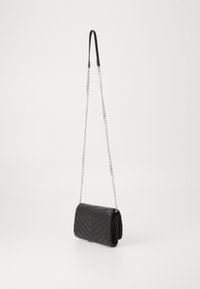 Svart crossbody-veske i lær med chevron-mønster, kjedehank og teksturert overflate. Har klaffelukking og en strømlinjeformet, rektangulær form.