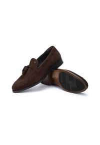 Mocasines de ante marrón con una textura suave, que presentan un borlas decorativa, detalles de costura y una suela de goma contrastante.