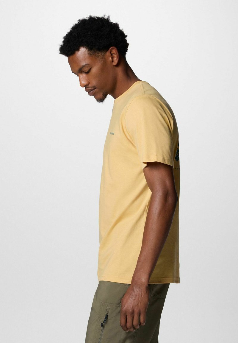 Gelbes Baumwoll-T-Shirt mit kurzen Ärmeln und rundem Halsausschnitt, versehen mit einem kleinen grafischen Akzent in der Nähe der Schulter. Weicher Stoff, lockere Passform.