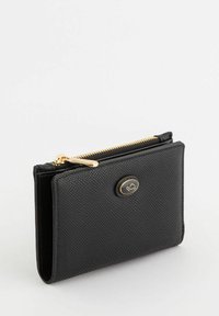 Billetera de piel negra con una superficie texturada, cremallera dorada y acento de logotipo ovalado. Forma compacta y rectangular con un acabado suave.