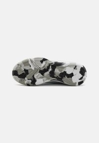 Shoe sole featuring a geometric tread pattern in black and white, with textured accents and a smooth midsole in light gray.