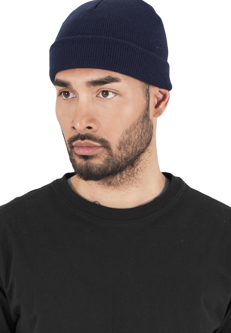 Marineblå ribbestrikket lue med tett passform og sømløs krone. Brukt sammen med en svart crew neck t-skjorte.